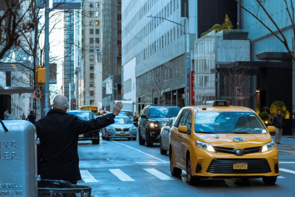 A man hailing a yellow taxi in bustling NYC street, capturing urban life.